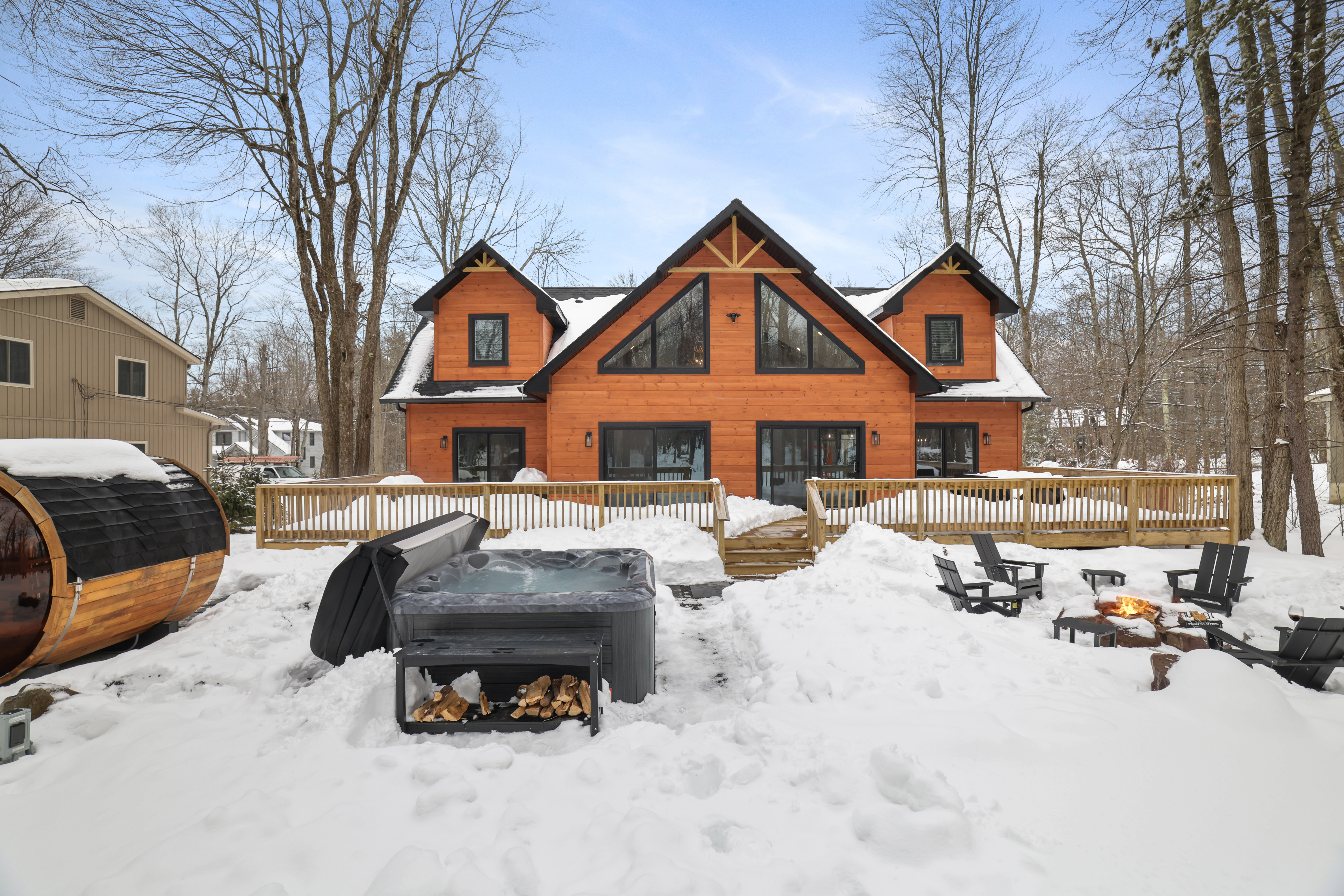 Back of house with hot tub, sauna, and firepit